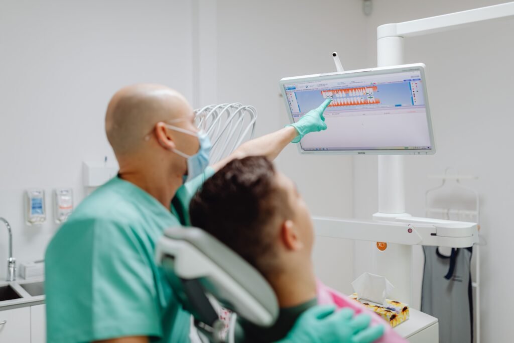 Dentist examining patient with dental imaging software in modern clinic.